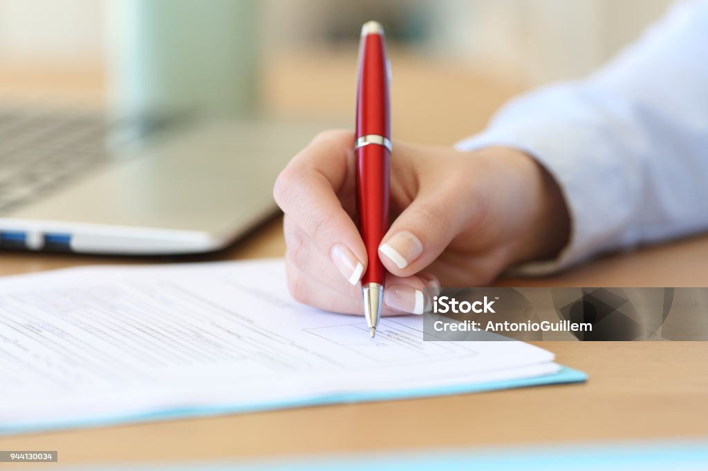 Businesswoman hand signing a contract on a desk Close up of a businesswoman hand signing a contract on a desk at office Signing Stock Photo