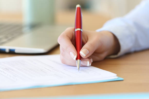 Businesswoman hand signing a contract on a desk Close up of a businesswoman hand signing a contract on a desk at office witness signature stock pictures, royalty-free photos & images