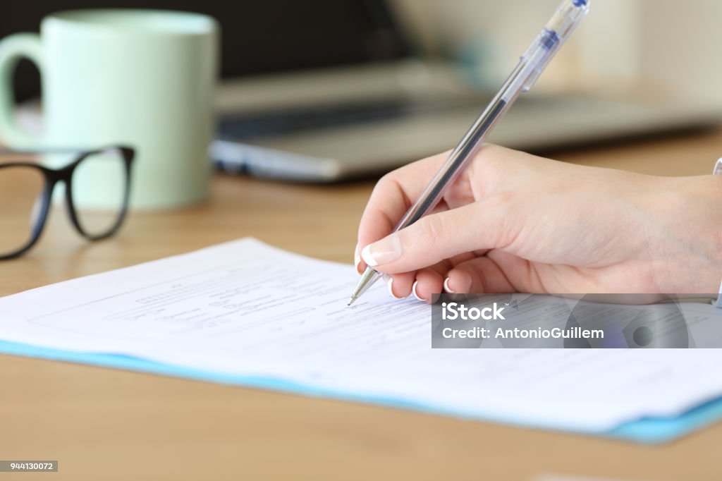 Cerca de una mano de mujer rellenando el formulario en una tabla - Foto de stock de Cuestionario libre de derechos