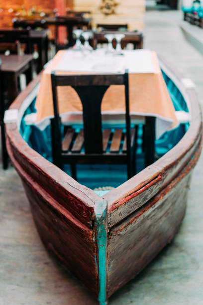 Unusual restaurant interior: dining table in the colorful fish boat. Marine ambience.