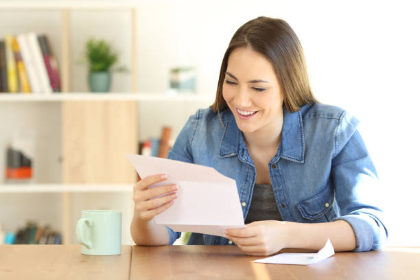 幸せな女の家で手紙を読む - opening mail letter envelope ストックフォトと画像