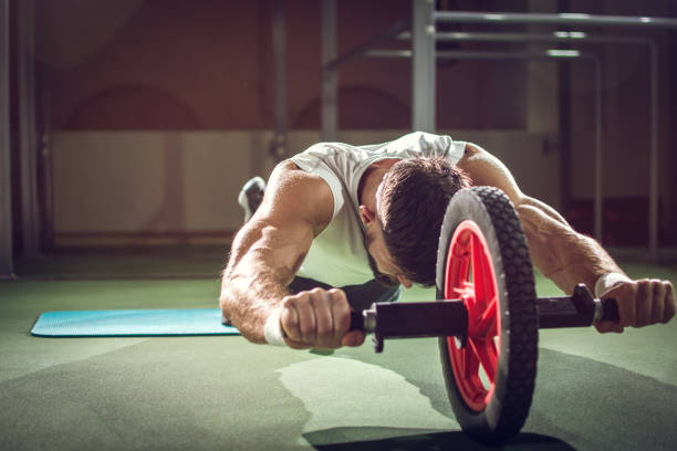 istock Handsome sportsman workout with abdominal roller in gym 944134756
