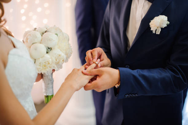 istock groom puts on a wedding ring on the finger of a beautiful bride 944143018
