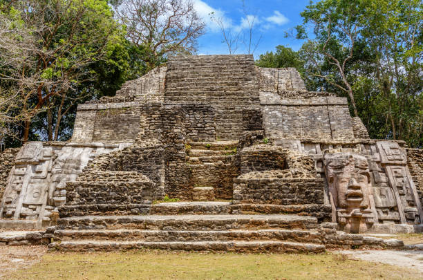 istock Old ancient stone Mayan pre-columbian civilization pyramid with carved face and ornament hidden in the forest, Lamanai archeological site, Orange Walk District, Belize 944147698