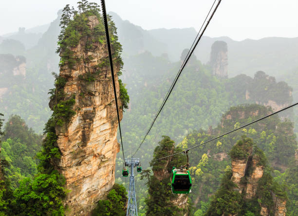 Cablecars on its way to the top among sandstone pillars and peak Cablecars on its way to the top among sandstone pillars and peaks with green trees and mountains panorama, Zhangjiajie national forest park, Hunan province, China8 zhangjiajie stock pictures, royalty-free photos & images