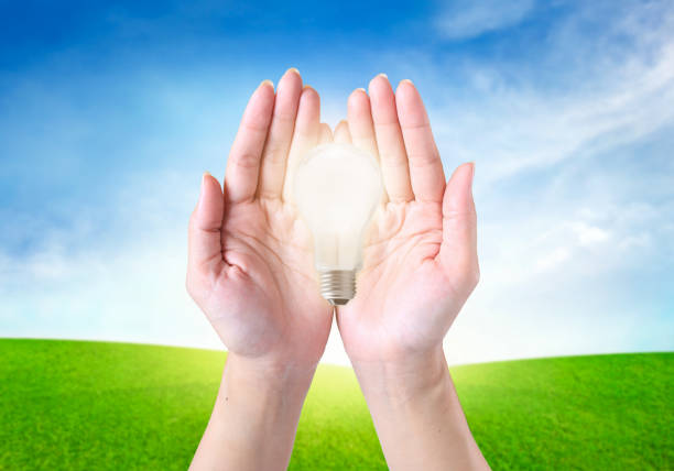 istock Cropped Hands Cupping Illuminated Light Bulb Against Sky 944148690