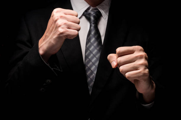 Close up of man in black suit with hand gesture on black background. Close up of man in black suit with hand gesture on black background. uncompromising stock pictures, royalty-free photos & images