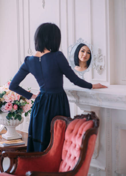 istock Young woman looking herself reflection in mirror at classic interior 944183070