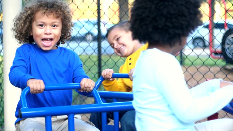 Multi-ethnic children on playground merry-go-round