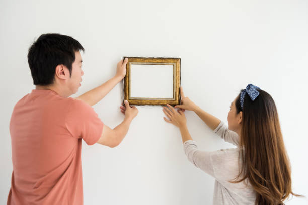istock couple attach photo frame at new house 944189260