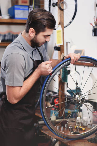 istock young mechanic in apron repairing bicycle wheel in workshop 944193672