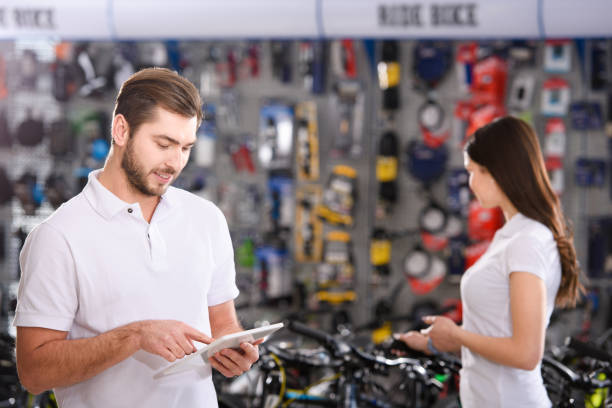 istock young manager using digital tablet while female colleague working behind in bicycle shop 944193884
