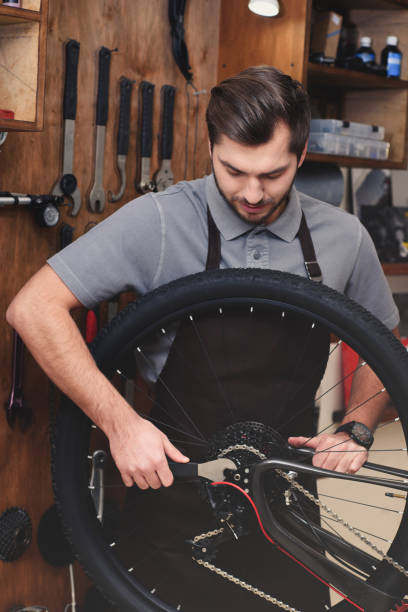 istock young man in apron fixing bicycle wheel and chain with wrench in workshop 944195282