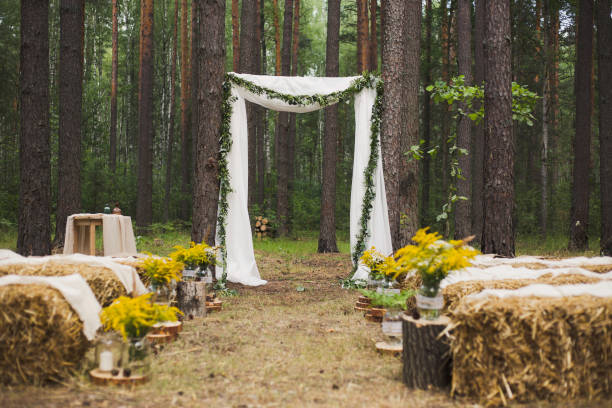 place in old autumn wood for wedding ceremony Beautifully decorated place in old autumn wood for wedding ceremony. Rustic style of elements of decor. Unusual seats made with straw. Horizontal color photography. country wedding arches stock pictures, royalty-free photos & images