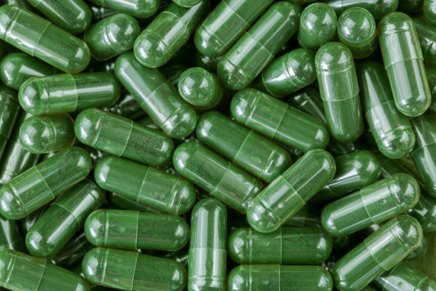 poudre vert spiruline, algue bleu - vert en capsules claires - chlorella spirulina bacterium algae nutritional supplement photos et images de collection