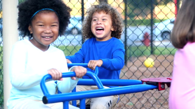 Multi-ethnic children on playground merry-go-round