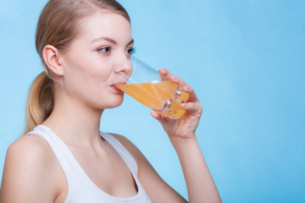 istock Woman drinking orange flavored drink or juice 944209552