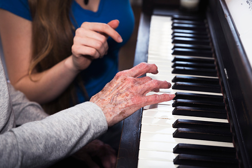 Close up of the hands of a granddaughter and grandmother working together to learn the piano.