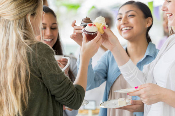 istock Women 'toast' with cupcakes during charity event 944221400