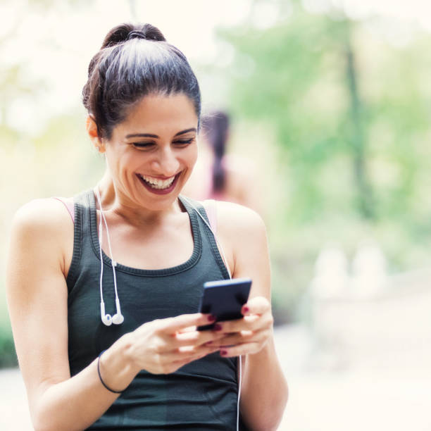 istock Mid adult woman texts while on morning walk 944222186