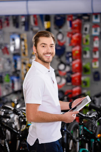 istock handsome young man holding digital tablet and smiling at camera in bicycle shop 944222224