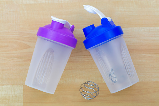 Plastic Bottle of protein shake mixer with metal shaker spiral spring ball to blend, on wooden background