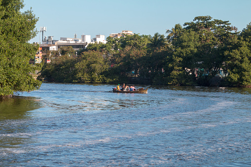 A group of people in a small fishing boat rowing across the Marapendi Lagoon in Barra da Tijuca, Rio de Janeiro