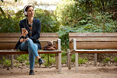 Woman listening to music on bench in park