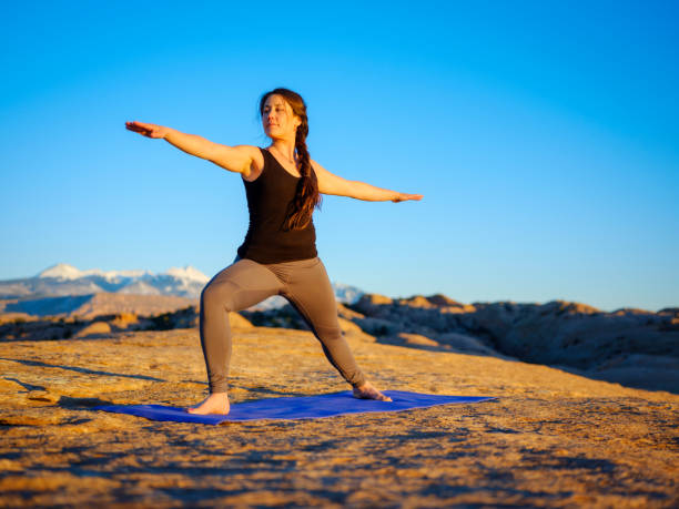 A young woman doing yoga at sunset on the red rocks of Moab, Utah USA.