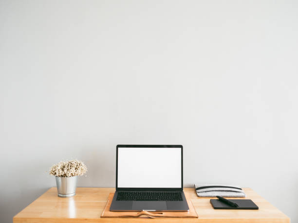 istock Laptop and some stationary tools on wooden work desk with empty gray wall as background. Concept of workspace and minimal office. 944252072