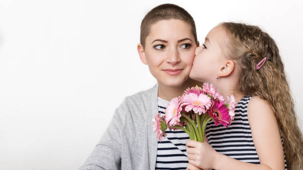 schönen muttertag, frauen tag oder geburtstag hintergrund. niedliche kleine mädchen geben mama, krebs-überlebenden, bouquet von rosa gerbera gänseblümchen. liebevolle mutter und tochter. - kissing child family isolated stock-fotos und bilder