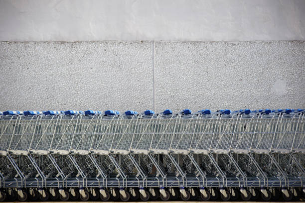 Shopping carts put together in a row in front of the bright wall of a shopping mall.