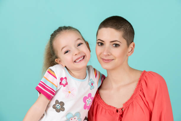 carina ragazza in età prescolare con sua madre, giovane paziente oncologico in remissione. concetto di paziente oncologico e supporto familiare. - cancer chemotherapy drug baby family foto e immagini stock