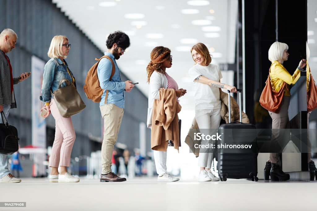 Queue of passengers Several passengers standing in queue while waiting for check-in registration before flight Waiting In Line Stock Photo