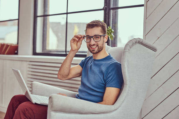 istock A happy young student sits on a chair and using a laptop. 944279692