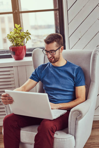 istock A happy young student sits on a chair and using a laptop. 944294390