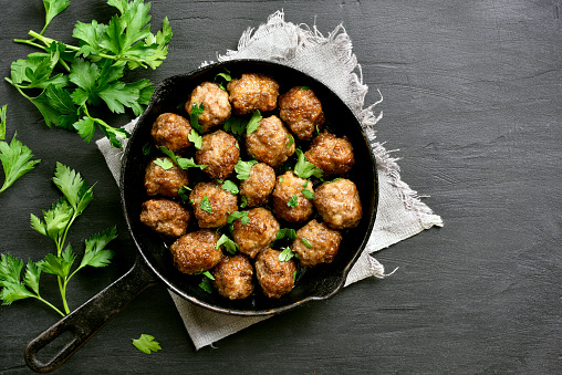 Meatballs in frying pan on black stone background with copy space. Top view, flat lay