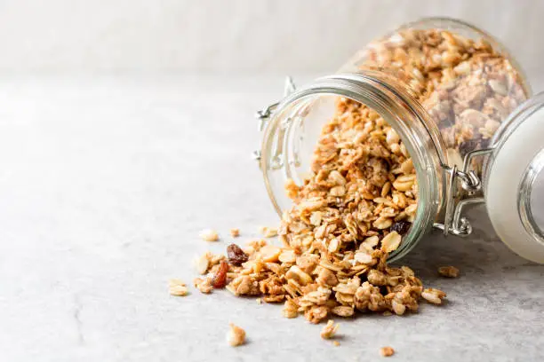 Fresh granola in glass jar on gray stone background. Selective focus. Copy space.