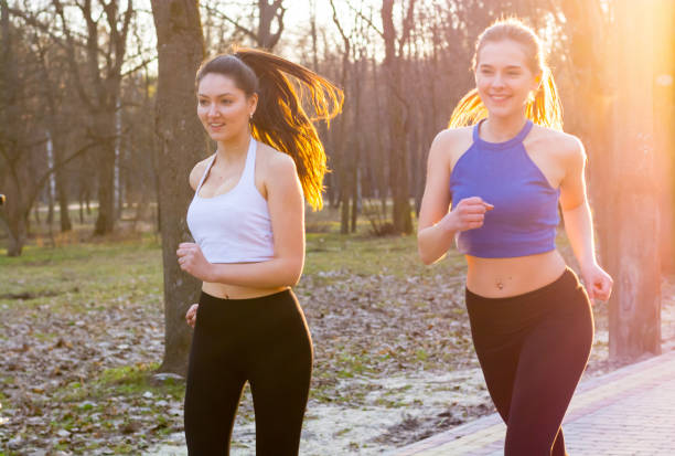 istock Two young women run along the path in the park at sunset 944311320
