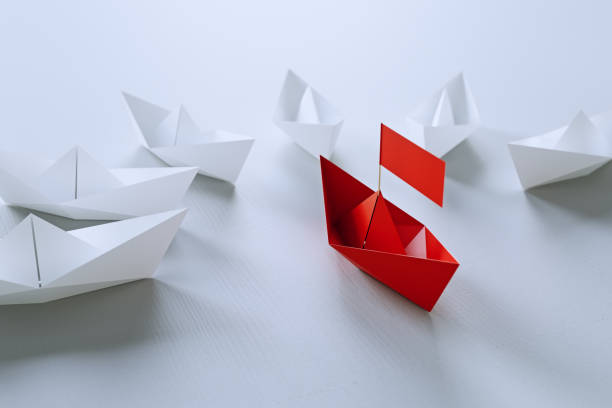 istock Leadership concept with red paper ship leading among white on white background.3d rendering. 944313676