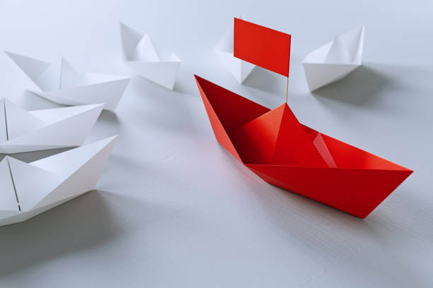 istock Leadership concept with red paper ship leading among white on white background.3d rendering. 944313938