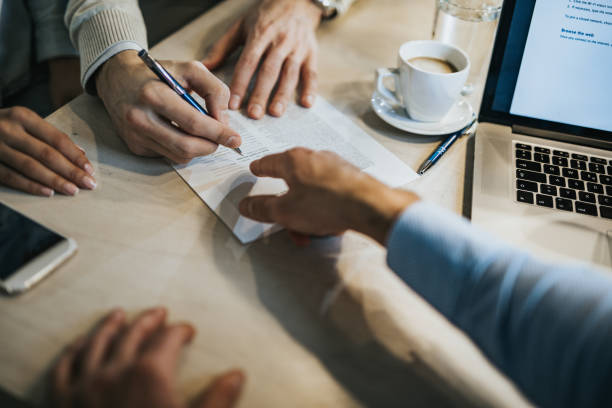 This is where you need to sign! Unrecognizable man signing a contract while financial advisor is aiming at the place he need to sign. lease agreement stock pictures, royalty-free photos & images