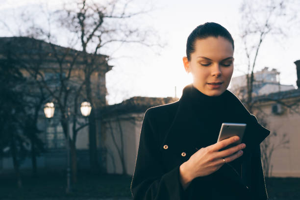 istock Woman uses smart phone while standing on the street 944314612
