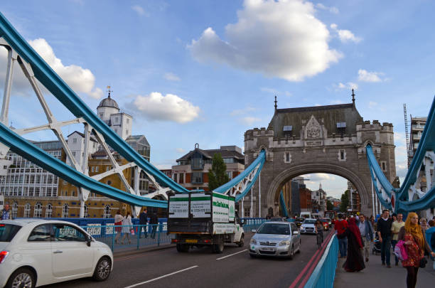 découvre une scène typique avec des voitures et des piétons sur le trottoir de la tower bridge - london england urban scene city life bus photos et images de collection