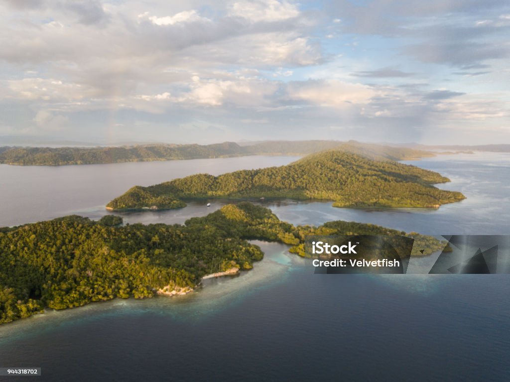 Aerial of Beautiful Islands in Raja Ampat Evening light shines on remote islands in Raja Ampat. This tropical region is known as the heart of the Coral Triangle due to its marine biodiversity. Papua New Guinea Stock Photo