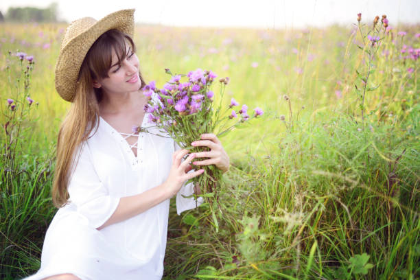 Beautiful Asian woman is smiling and relaxing in blooming purple Murdannia giganteum flowers field
