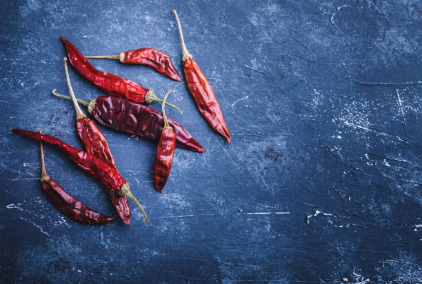 istock Dried chili peppers on blue concrete background 944340566