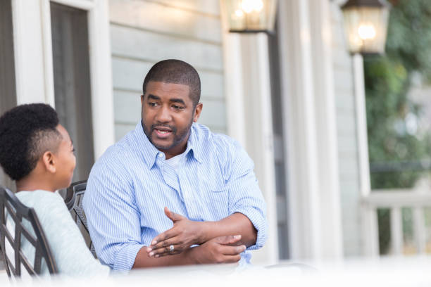 istock Father talks with preteen son on front porch 944350942