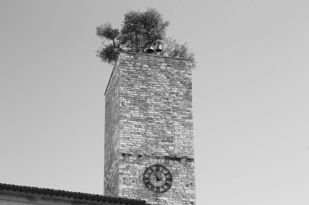 Isolated clock tower with a garden and bells on the roof (Spello, Umbria, Italy)