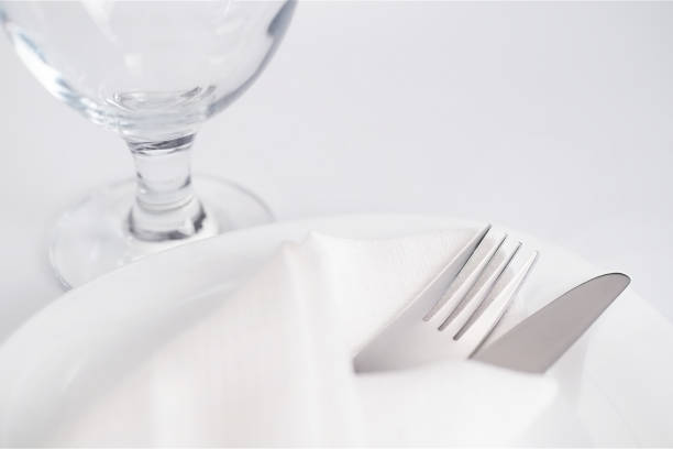 istock Drinking glass and cutlery into white napkin on white plate 944352030